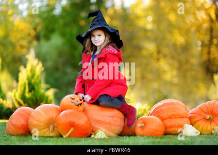 Adorabile bambina indossando il costume di halloween per divertirsi in un orto di zucche Foto Stock