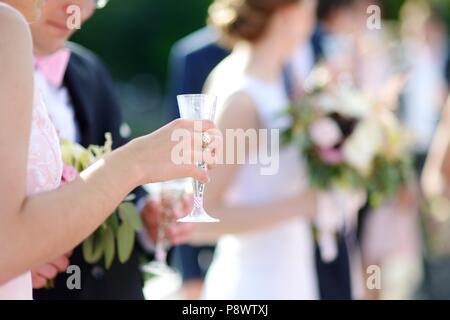 Donna con in mano un bicchiere di champagne a qualche evento festivo, un party o un ricevimento di nozze Foto Stock