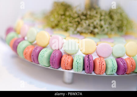 In stile tradizionale francese macarons su una torta di vetro stand Foto Stock