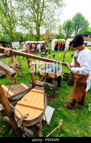 Storia viva, outdoor rievocazione evento. L uomo medievale, fabbro, usando soffietto e forge per rendere le armi di ferro. Foto Stock