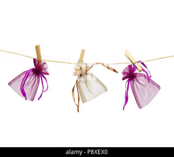 Tre poco colorato buste regalo appeso a una fune con clothespins isolati su sfondo bianco. Foto Stock