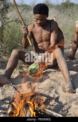Botswana: Un Naro-Buschmen vicino a Ghanzi e prateria Safari Lodge è la tostatura un melone. Foto Stock
