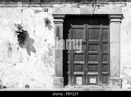 Porta in legno in stile rustico spagnolo blu parete coloniale, Antigua, Guatemala, America centrale in bianco e nero Foto Stock