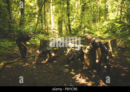 Montare gli uomini strisciare sotto la rete durante la fase di corsa a ostacoli Foto Stock