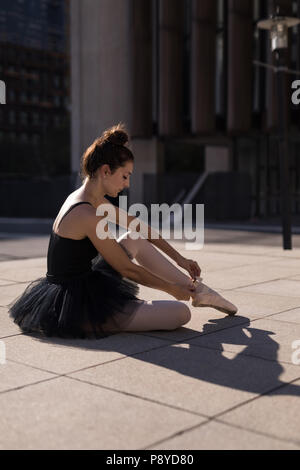 Femmina danzatore di balletto di legatura del nastro sul suo scarpe da ballo Foto Stock