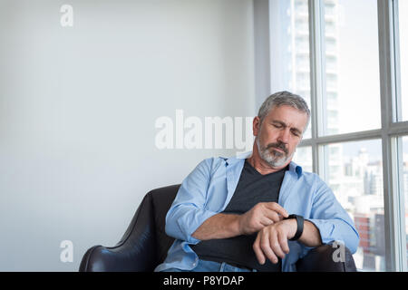 Uomo che utilizza smartwatch a casa Foto Stock