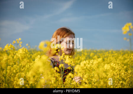 Donna di toccare i raccolti nel campo di senape in una giornata di sole Foto Stock