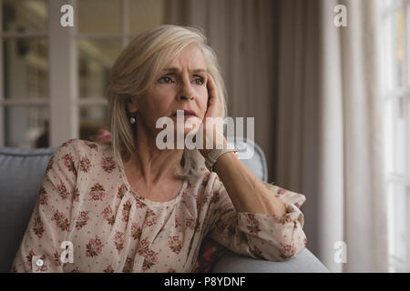 Preoccupato senior donna seduta sul divano di casa Foto Stock
