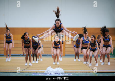 Adolescente cheerleaders dancing, acrobacy, mosse acrobatiche cheerleaders in blu in aria Foto Stock