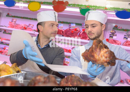 Macellaio di insegnamento di una giovane come vendere la carne Foto Stock