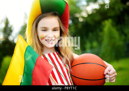 Funny bambina il supporto e il tifo nazionale la sua squadra di basket durante il campionato di pallacanestro. Carino team lituano ventola. Foto Stock