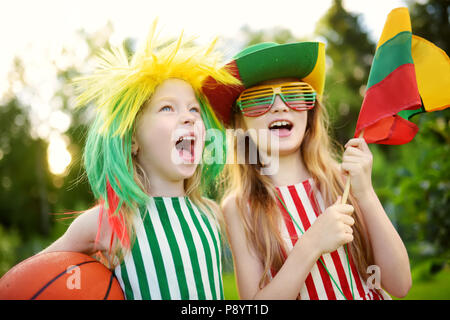 Due divertenti piccole sorelle di supporto e rasserenanti loro nazionale della squadra di basket durante il campionato di pallacanestro. Due graziosi team lituano fan. Foto Stock