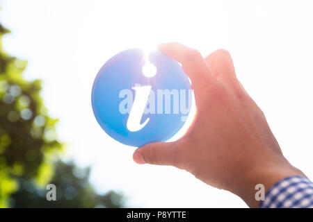 Close-up di una mano di un uomo azienda blu Icona informazioni Foto Stock