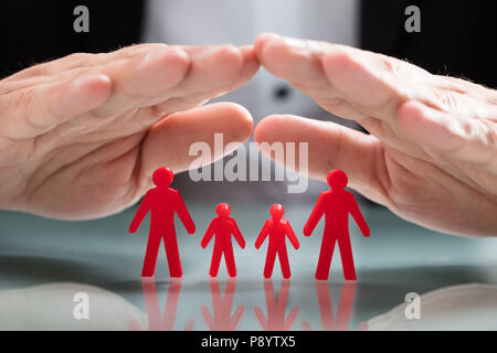 Close-up di un imprenditore della mano rosso di protezione famiglia cifre Foto Stock