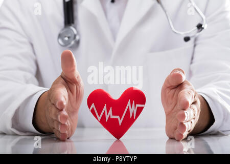 Medico della mano rosso di protezione frequenza cardiaca sulla scrivania Foto Stock