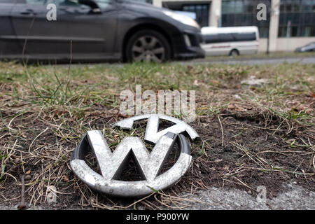 Berlino, Germania, rotto la griglia del grill emblema di una Volkswagen giace sulla striscia di verde di una strada Foto Stock