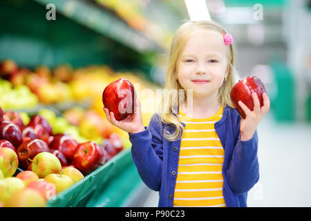 Bambina scelta di mele mature in un negozio di generi alimentari o supermercati Foto Stock