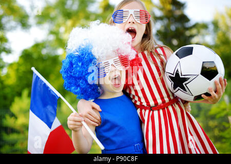 Due divertenti piccole sorelle di supporto e il tifo la loro squadra nazionale di calcio durante il campionato di calcio Foto Stock