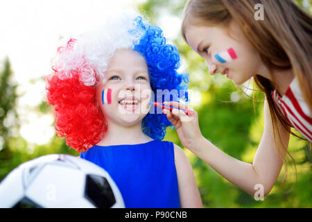 Due divertenti piccole sorelle di supporto e il tifo la loro squadra nazionale di calcio durante il campionato di calcio Foto Stock