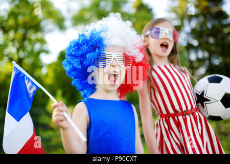 Due divertenti piccole sorelle di supporto e il tifo la loro squadra nazionale di calcio durante il campionato di calcio Foto Stock