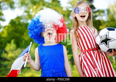 Due divertenti piccole sorelle di supporto e il tifo la loro squadra nazionale di calcio durante il campionato di calcio Foto Stock