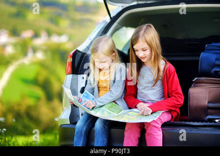 Due adorabili poco sorelle ad esplorare una mappa prima di andare in vacanza con i loro genitori. Due bambini di guardare avanti per un viaggio su strada o in viaggio. Foto Stock