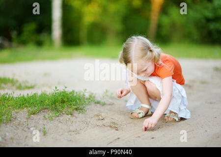 Adorabile bambina cattura poco babyfrogs sulla bellissima giornata estiva in foresta Foto Stock