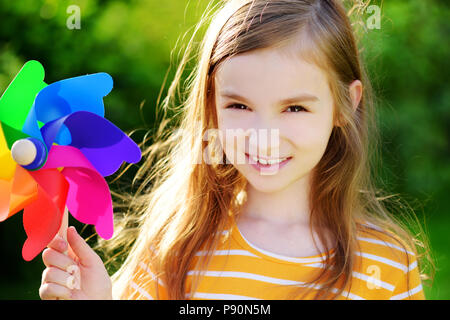 Adorabile bambina azienda giocattolo colorata girandola sul sole e caldo giorno d'estate Foto Stock