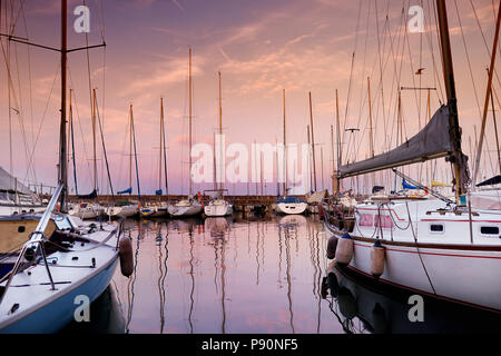 Piccole barche nel porto di Desenzano del Garda su autunno magnifico tramonto, Lombardia, Italia Foto Stock