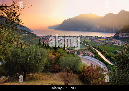 Scenic vista aerea di Riva del Garda, situato su una sponda del lago di Garda, circondato da bellissime montagne rocciose. Spettacolare tramonto d'autunno. Foto Stock