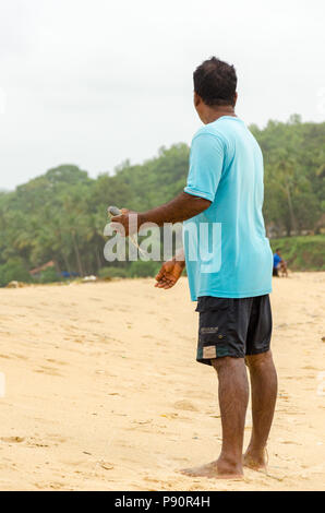 Ritratto di un locale di Goa fisherman tenendo un pesce in spiaggia Betul, Cavelossim, Goa, India Foto Stock