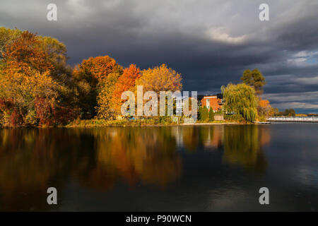Nuvole scure e colori autunnali intorno al lago di Boivin, Granby, Eastern Townships, Quebec, Canada. Yamaska estuario del fiume. Foto Stock