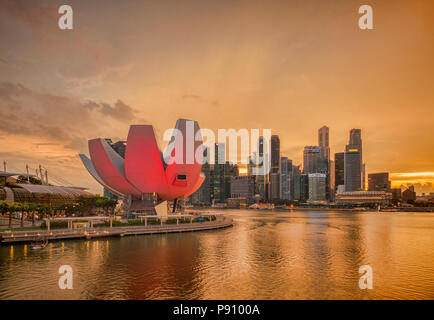 Lo skyline di Singapore sotto un cielo arancione come una tempesta inizia con l'arte e il museo della scienza illuminata in rosa. Architetto è stato Moshe Safdie. Foto Stock