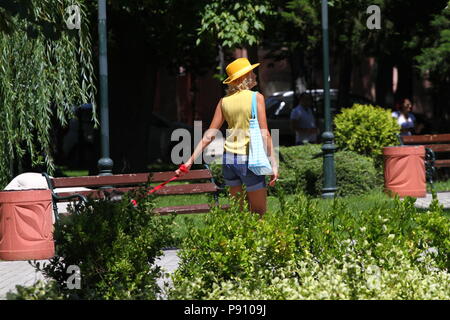 Irriconoscibile donna con cappello giallo e pantaloncini il resto e fa una passeggiata nel parco con un cane. Persona non identificata una passeggiata all'aperto in natura. Sport Foto Stock