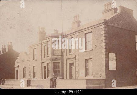 L'annata 1905 fotografia di un poliziotto si fermò di fronte a una stazione di polizia, corte casa accanto. Foto Stock