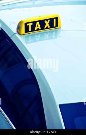 Giallo taxi segno sul tetto di una vettura blu Foto Stock