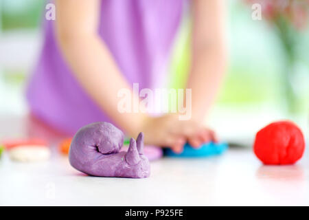 Carino bambina divertendosi con colorati di creta per modellare in un asilo nido. Creative kid lo stampaggio a casa. Il bambino gioca con la plastilina o la pasta. Foto Stock