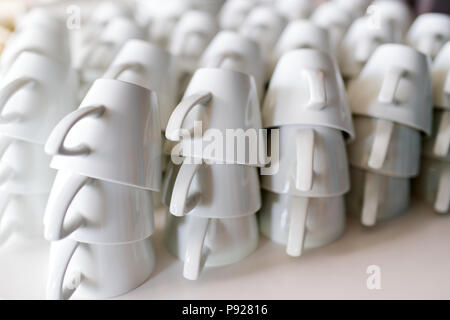 Molte righe di bianco puro e tazze da caffè sul tavolo bianco Foto Stock