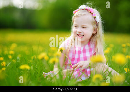 Adorabile bambina in fioritura di tarassaco prato sulla splendida giornata di primavera. Bambino divertimento all'aperto la raccolta dei fiori freschi. Foto Stock