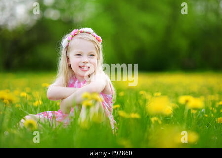 Adorabile bambina in fioritura di tarassaco prato sulla splendida giornata di primavera. Bambino divertimento all'aperto la raccolta dei fiori freschi. Foto Stock