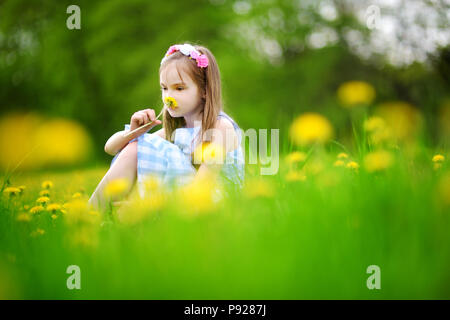 Adorabile bambina in fioritura di tarassaco prato sulla splendida giornata di primavera. Bambino divertimento all'aperto la raccolta dei fiori freschi. Foto Stock