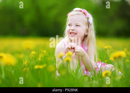 Adorabile bambina in fioritura di tarassaco prato sulla splendida giornata di primavera. Bambino divertimento all'aperto la raccolta dei fiori freschi. Foto Stock