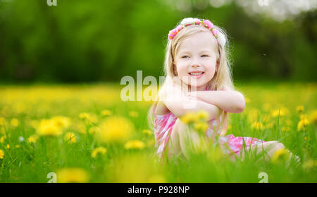 Adorabile bambina in fioritura di tarassaco prato sulla splendida giornata di primavera. Bambino divertimento all'aperto la raccolta dei fiori freschi. Foto Stock