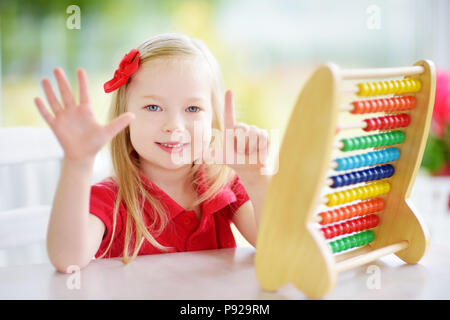 Carino bambina gioca con abacus a casa. Smart bambino ad imparare a contare. Preschooler divertirsi con il giocattolo educativo a casa o asilo nido. Foto Stock