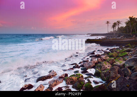 Di un bel colore rosa colorato di onde che si infrangono sulla spiaggia rocciosa di sunrise sulla costa est della Big Island delle Hawaii, STATI UNITI D'AMERICA Foto Stock