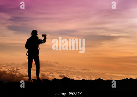 Tourist ammirando il tramonto mozzafiato vedute dal Mauna Kea, un vulcano dormiente sull'isola di Hawaii. Il picco del Mauna Kea Peak è il più alto po Foto Stock