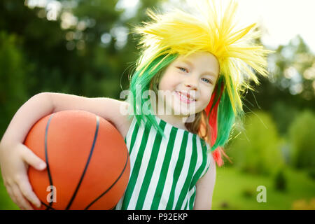 Funny bambina il supporto e il tifo nazionale la sua squadra di basket durante il campionato di pallacanestro. Carino team lituano ventola. Foto Stock