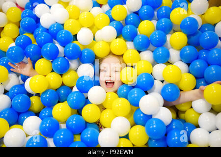 Felice bambina divertendosi in palla in buca kids giochi al coperto