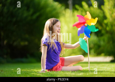 Adorabile bambina azienda giocattolo colorata girandola sul sole e caldo giorno d'estate Foto Stock