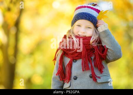 Carino bambina divertirsi sulla bellissima giornata autunnale. Bambino felice giocando in autunno park. Raccolta di capretto giallo caduta delle foglie. Attività di autunno per chil Foto Stock